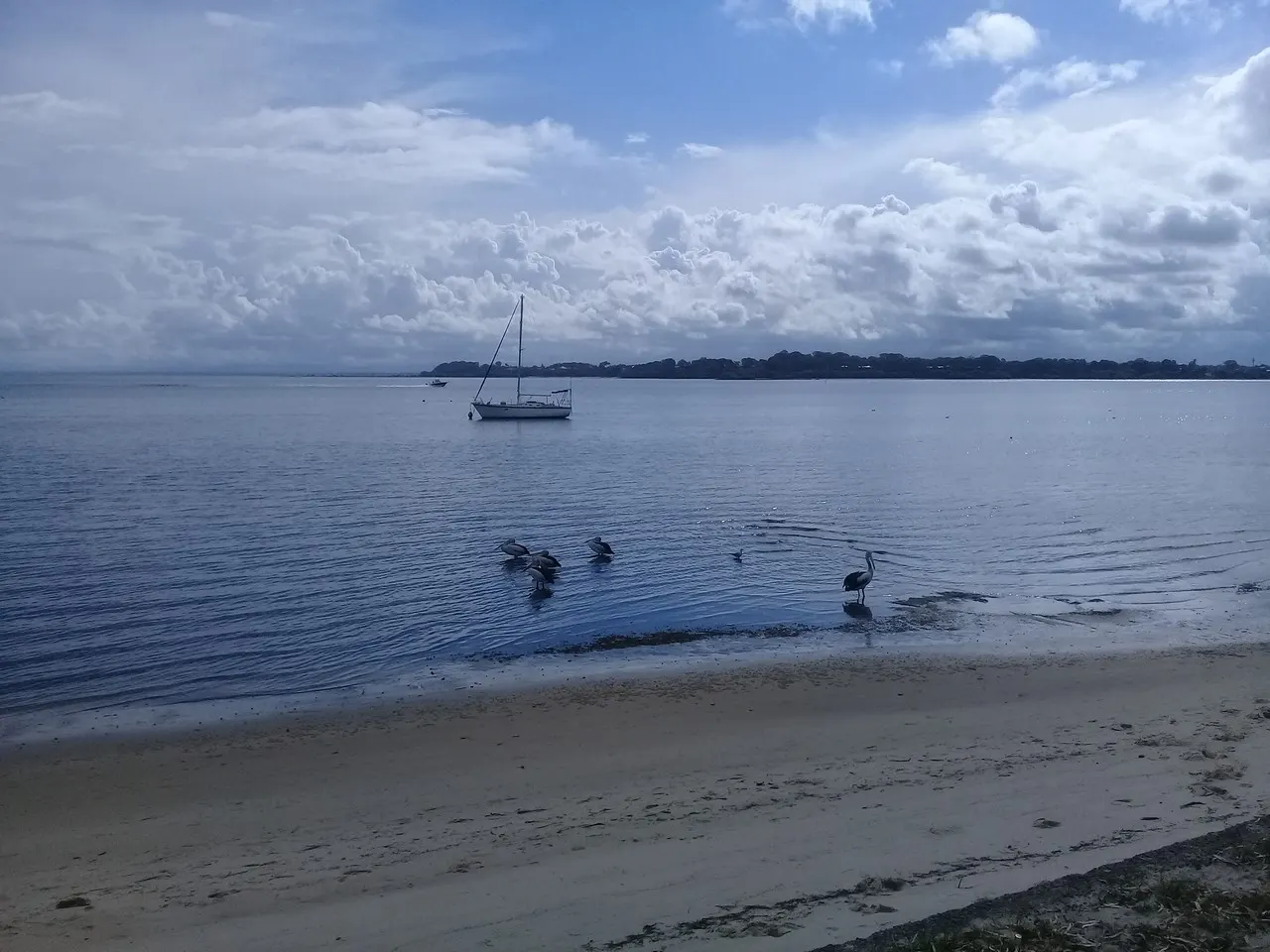 Cloudy sky over the beach and moored yacht at Bribie Island